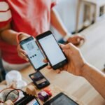 two person's hands holding turned-on phones